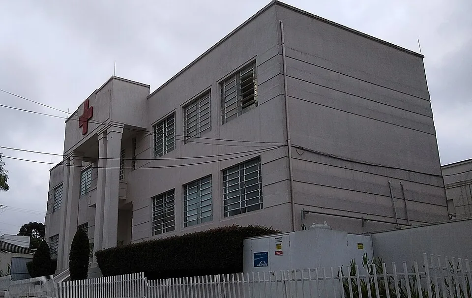 Fachada modernista do Hospital da Cruz Vermelha em Curitiba, com uma cruz vermelha grande no alto da entrada