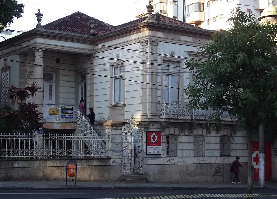 Casarão histórico da Cruz Vermelha Brasileira em Porto Alegre, com uma placa vermelha com o emblema e o nome junto ao portão e uma cruz vermelha pintada no portão