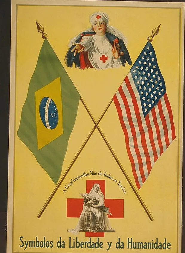 Cartaz colorido da Primeira Guerra Mundial, sobre fundo amarelo: bandeiras do Brasil e dos Estados Unidos cruzadas, uma enfermeira da Cruz Vermelha de braços abertos no alto e, embaixo, uma figura feminina sentada sobre uma cruz vermelha, com os títulos “A Cruz Vermelha, Mãe de Todas as Nações” e “Symbolos da Liberdade y da Humanidade”