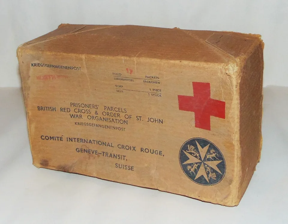 Caixa de encomenda da Cruz Vermelha Britânica para prisioneiros de guerra, com a cruz vermelha, o emblema da Ordem de São João e a inscrição Comité International Croix Rouge, Genève-Transit