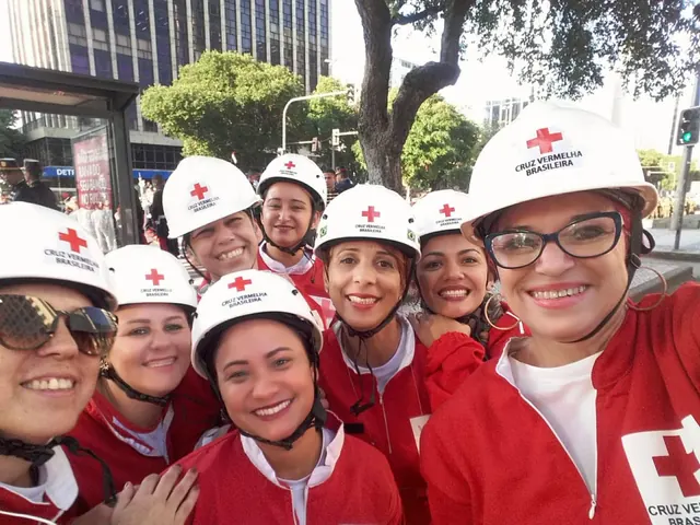 Voluntárias sorridentes com capacete branco e uniforme vermelho da Cruz Vermelha