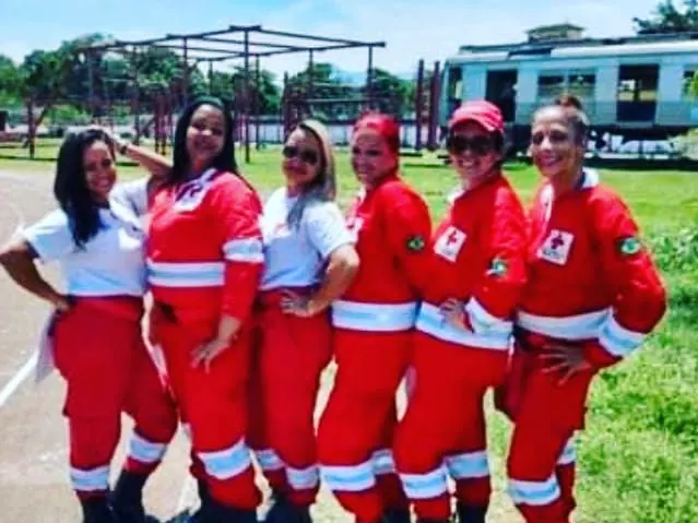 Voluntárias com uniforme de campo vermelho da Cruz Vermelha, ao ar livre