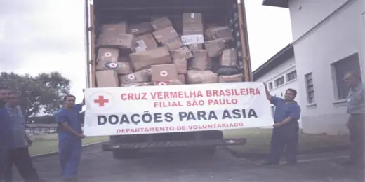 Lorry with boxes visible on the load and a banner reading Doações para Ásia, Cruz Vermelha Brasileira, Filial São Paulo