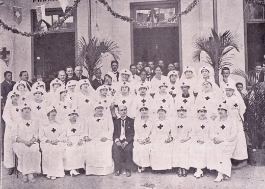 Large group of nurses and officers posing seated and standing, with a man at the centre