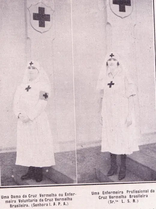 Two women standing side by side in white uniforms with veils and the red cross