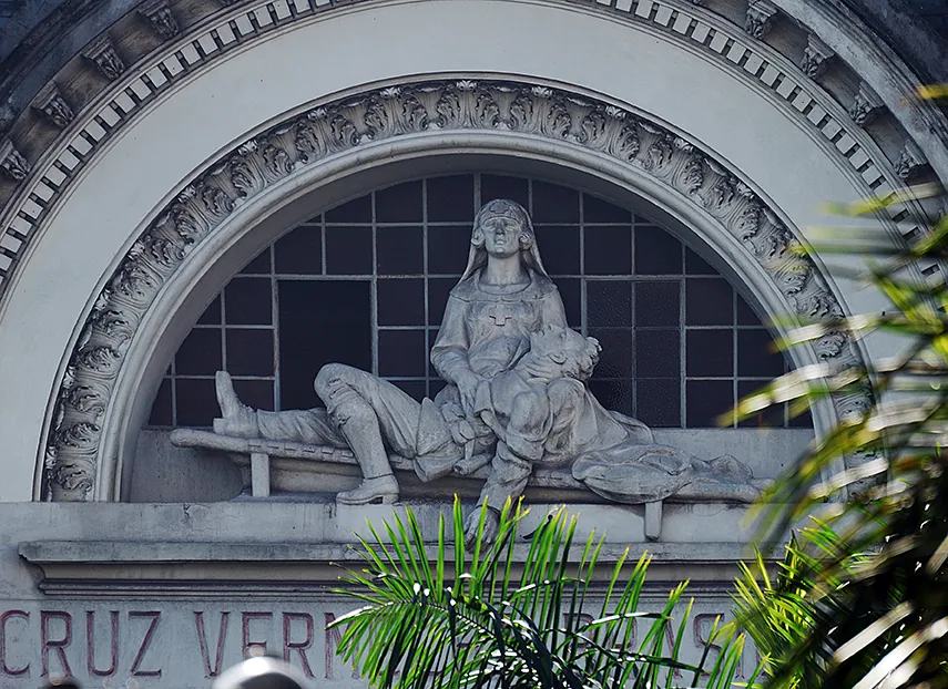 Grupo escultórico sobre a entrada do Palácio: uma enfermeira amparando um ferido, sob o arco da fachada