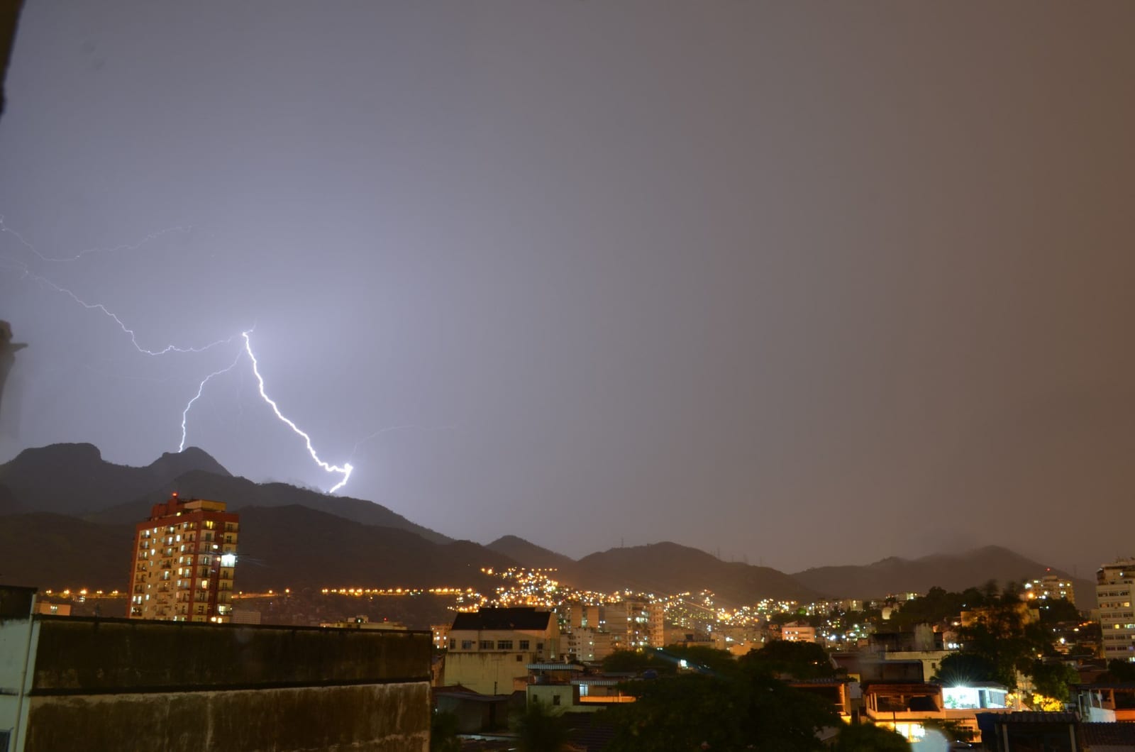 Raio cruzando o céu de tempestade sobre as montanhas e a cidade do Rio de Janeiro ao anoitecer