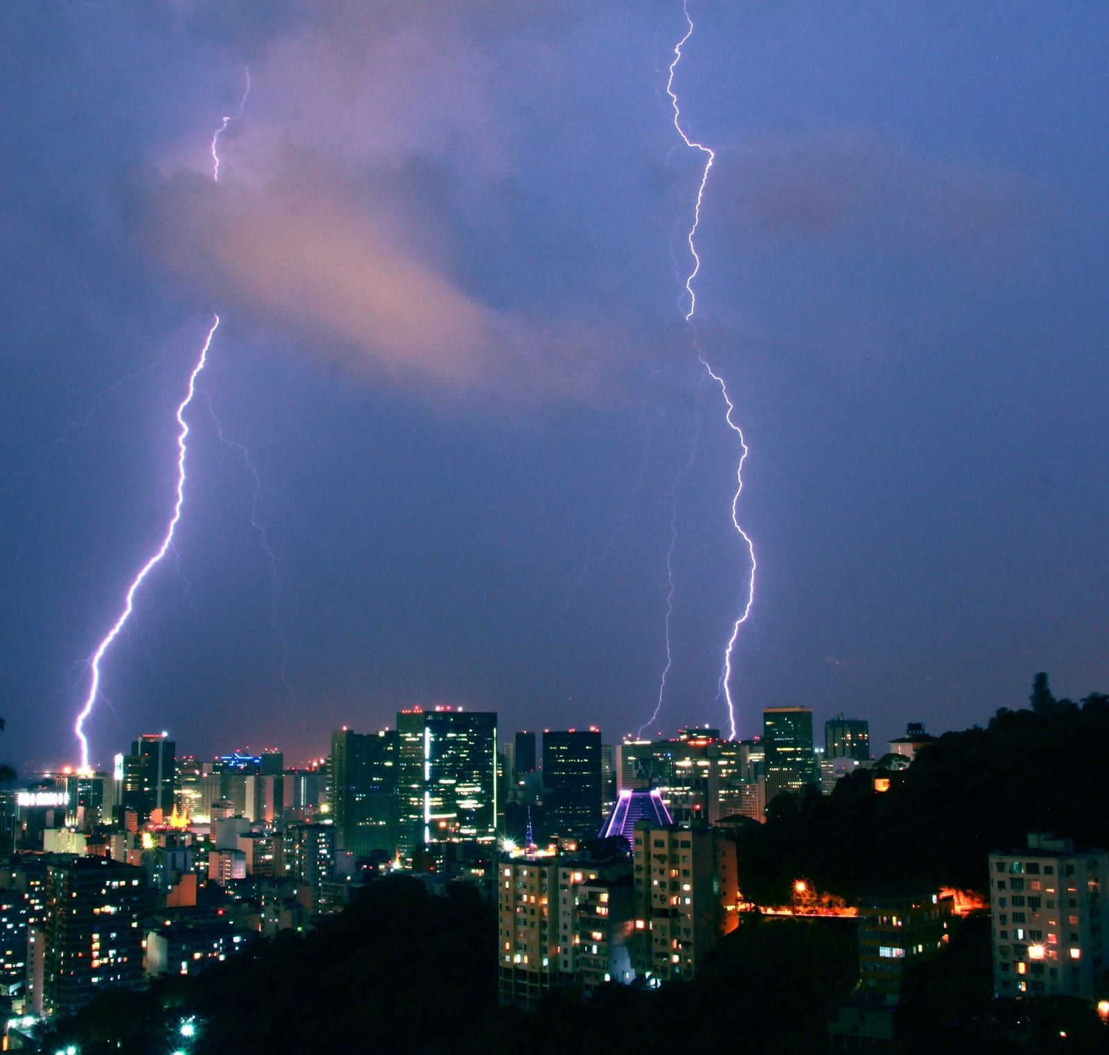 Raios caindo sobre os prédios de uma cidade à noite, vistos do Rio de Janeiro