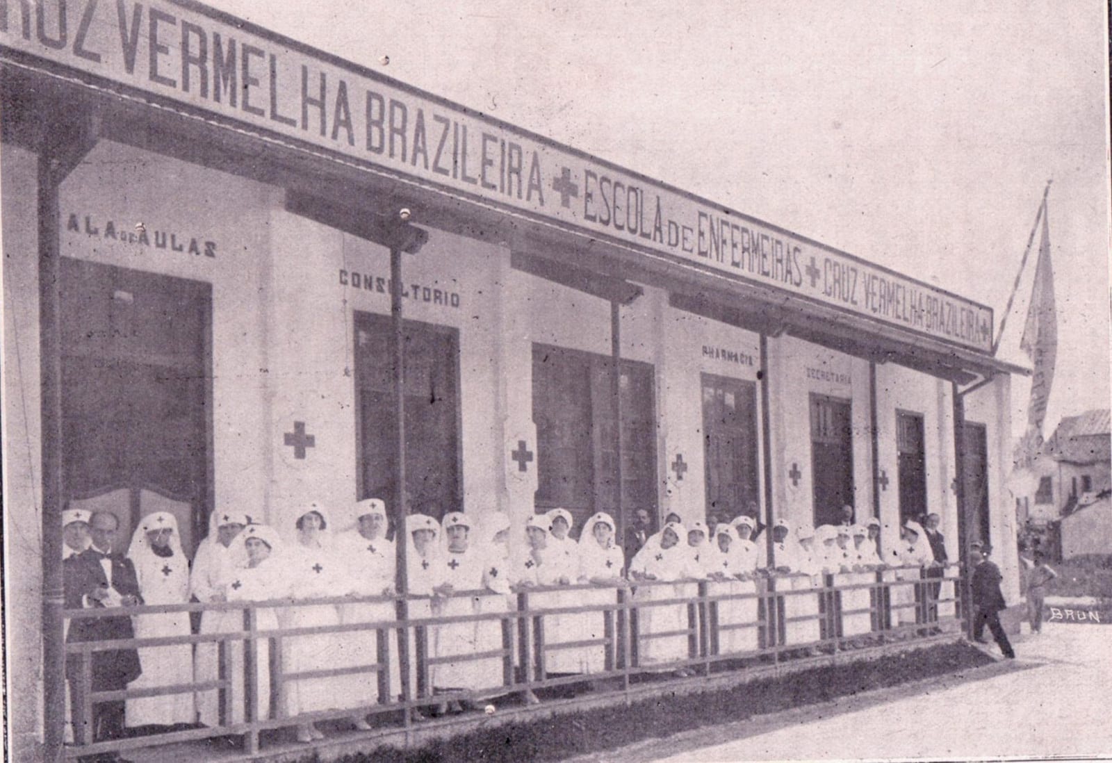 Enfermeiras de branco enfileiradas na varanda do prédio da Escola de Enfermeiras da Cruz Vermelha Brasileira, em foto histórica